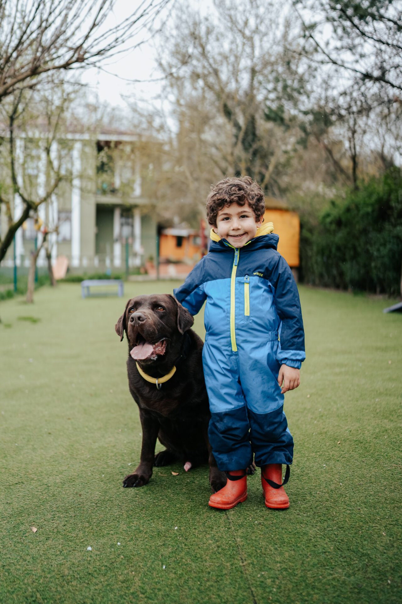 Child and dog standing and smiling in a backyard